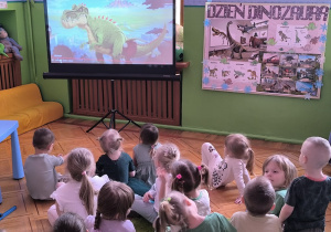 dzieci oglądają film edukacyjny o dinozaurach