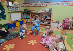 chłopiec prezentuje rówieśnikom książkę o Misiu Uszatku