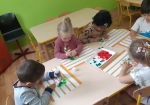 dzieci wyklejają bibułą i plasteliną obrazki jabłek