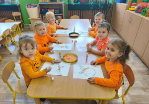 dzieci wyklejają na pomarańczowo kontur marchewki i pomarańczy