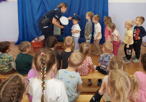 dzieci przymierzają różne policyjne nakrycia głowy