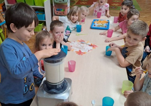 chłopiec miksuje owoce w blenderze