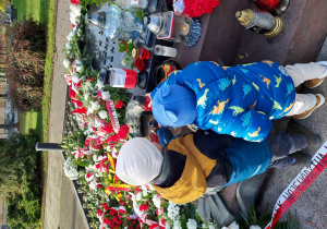 chłopcy kładą znicze