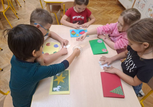 dzieci naklejają elementy z papiery na kartki