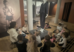 dzieci słuchają opowieści o butach w muzeum