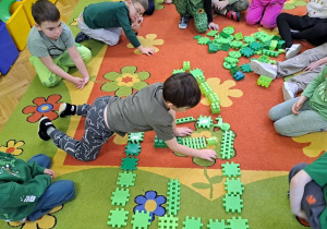 dzieci układają dom z zielonych klocków