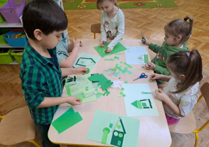 dzieci układają wycięte zielone elementy pracy plastycznej