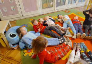 dzieci tworzą słoneczko układając się na dywanie