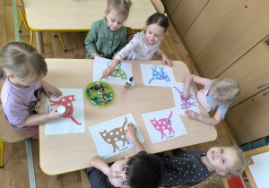 dzieci wyklejają koty pomponami