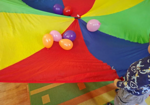 dzieci bawią się chustą oraz balonami