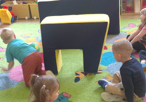 dzieci toczą piłke w tunelu