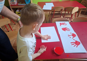 dziecko odbija dłoń z farbą na kartonie